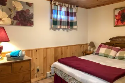 a bedroom with a bed and a table with a lamp at Pet-Friendly New York Cabin with Hot Tub and Game Room in Maplecrest