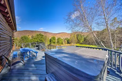 a patio with a table and chairs on a deck at Pet-Friendly New York Cabin with Hot Tub and Game Room in Maplecrest