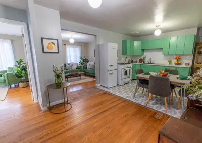 a kitchen and living room with green cabinets and a table at The Springs Motel in New Ashford