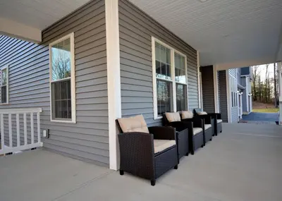 a porch with wicker chairs on a house at 9 Bedroom Saratoga Retreat, In-Ground Heated Pool, HotTub, Firepit, Gourmet Kitchen, Private Office in Saratoga Springs