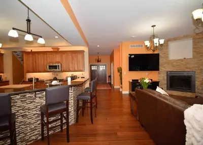 a kitchen and living room with a bar and chairs at 9 Bedroom Saratoga Retreat, In-Ground Heated Pool, HotTub, Firepit, Gourmet Kitchen, Private Office in Saratoga Springs