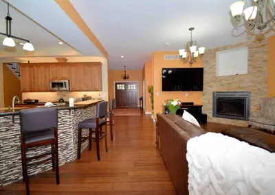 a living room and kitchen with a couch and a fireplace at 9 Bedroom Saratoga Retreat, In-Ground Heated Pool, HotTub, Firepit, Gourmet Kitchen, Private Office in Saratoga Springs