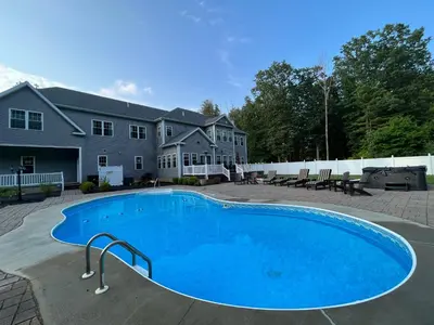 a large blue swimming pool in front of a house at 9 Bedroom Saratoga Retreat, In-Ground Heated Pool, HotTub, Firepit, Gourmet Kitchen, Private Office in Saratoga Springs
