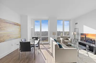 an apartment living room with white furniture and windows at Global Luxury Suites Downtown White Plains in White Plains