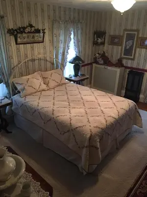 a bedroom with a bed with a white comforter at Raindrops On Roses Bed & Breakfast in Herkimer