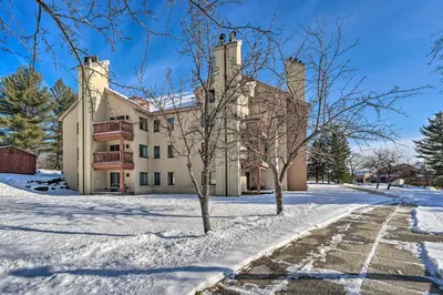 a large house in the snow with two trees at Steps to Ski Shuttle! Snow Mountain Village Condo in Dover