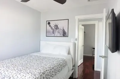 a white bedroom with a bed and a tv at Best Home To Visit NYC+Hot Tub+EWR Airport+Free Parking in Hillside