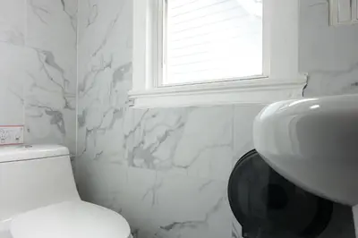 a bathroom with a toilet and a sink and a window at Best Home To Visit NYC+Hot Tub+EWR Airport+Free Parking in Hillside