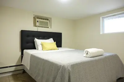a bedroom with a bed with a black headboard and yellow pillows at Best EWR Airport Studio-Hot Tub-Free Parking in Hillside