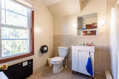 a bathroom with a toilet and a window at 1 Bus Stop To NYC-Hot Tub-EWR Airport-Free Parking in Hillside