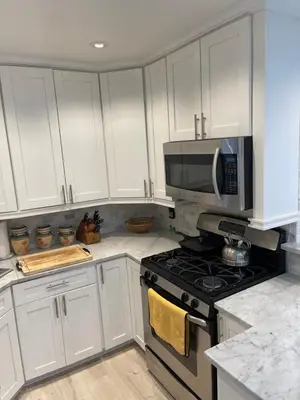 a kitchen with white cabinets and a stove and microwave at Renovated Jacuzzi Tub Home NYC-LGA-JFK Washer-Dryer in Kew Gardens