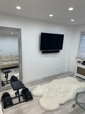 a living room with a television on a wall at Renovated Jacuzzi Tub Home NYC-LGA-JFK Washer-Dryer in Kew Gardens