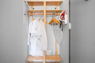 a closet with a wooden rack and white clothes at The Modernist Hotel in Long Island City