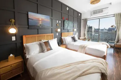 two beds in a room with a tv on the wall at The Modernist Hotel in Long Island City