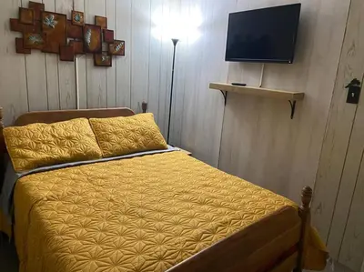 a bedroom with a bed with a yellow comforter and a television at Clubhouse Lakeview Chalet in East Stroudsburg