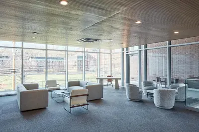 a waiting room with chairs and tables and windows at Harmony Lofts on Jackson 2 in Hoboken