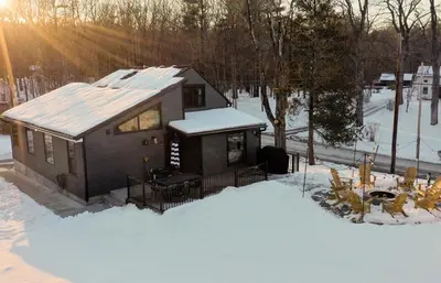 a small house in the snow with the sun behind it at Acorn Lodge - Luxury Cabin, Catskills, Windham Mountain, Hunter Mountain in Cairo