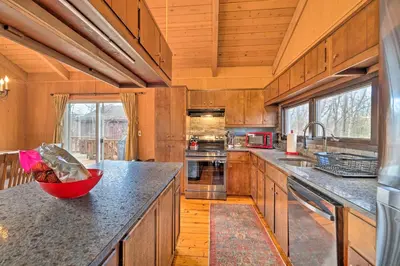 a kitchen with wooden cabinets and a red bowl on the counter at Fire Pit and Grill Lakefront Poconos Cottage! in East Stroudsburg