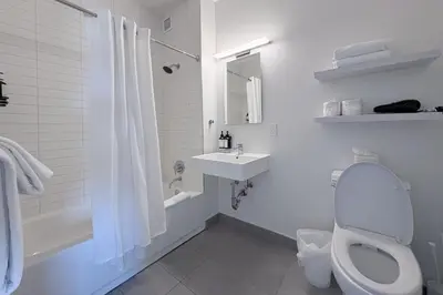 a white bathroom with a toilet and a sink at Court Square Hotel Long Island City New York , Belvilla District 6 Formerly Sonder in Long Island City