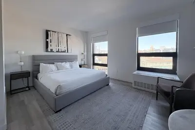 a bedroom with a bed and a desk and two windows at Court Square Hotel Long Island City New York , Belvilla District 6 Formerly Sonder in Long Island City
