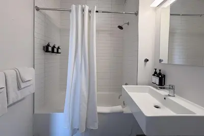 a bathroom with a sink and a white shower curtain at Court Square Hotel Long Island City New York , Belvilla District 6 Formerly Sonder in Long Island City