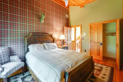 a bedroom with a bed and a chair in a room at Luxury Log Cabin with EV Charger and Mtn Views! in Blairstown