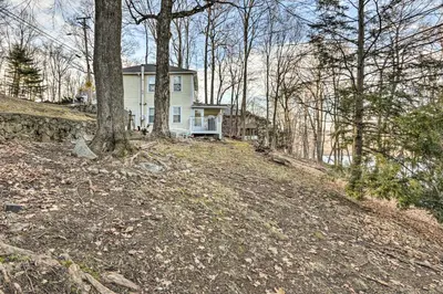 a white house on top of a hill with trees at Charming Danbury Cottage with Lake Kenosia Access! in Danbury