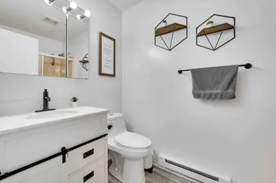a bathroom with a toilet and a sink and a mirror at Cozy Poconos Mountain House with 3 bedrooms in Tobyhanna