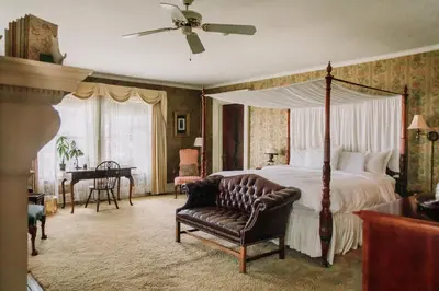 a bedroom with a canopy bed and a chair at South Shire in Bennington