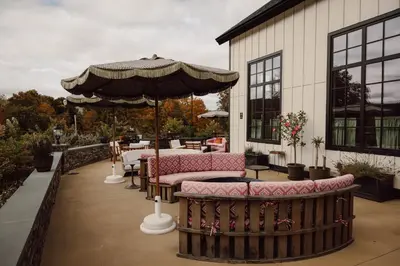 a patio with an umbrella and tables and chairs at Berkshires Untold in Lenox