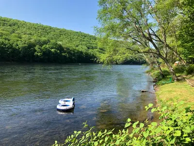 a small boat in the middle of a river at Slumberland at the River's Edge in Pond Eddy