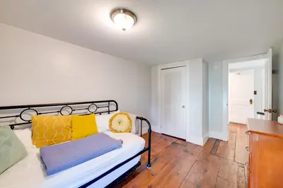 a bedroom with a bed with yellow and blue pillows at Less Than 4 Mi to Cooperstown Charming Historic Home! in Fly Creek