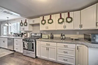 a kitchen with white cabinets and wreaths on the wall at A-Frame Cabin with Hot Tub 5 Mi to Waterford! in Melrose