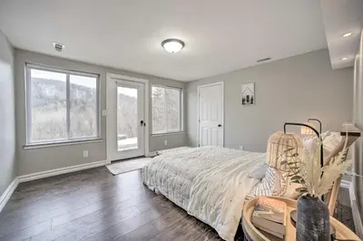 a bedroom with a bed and a table and windows at A-Frame Cabin with Hot Tub 5 Mi to Waterford! in Melrose