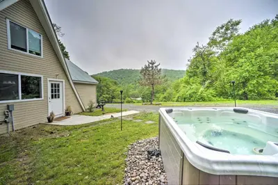 a hot tub in a yard next to a house at A-Frame Cabin with Hot Tub 5 Mi to Waterford! in Melrose
