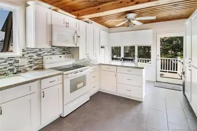 a kitchen with white cabinets and white appliances at Cozy Beach - Direct Waterfront! in East Haven