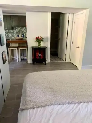 a bedroom with a fireplace in a room with a kitchen at The Suite at Pound Ridge in Pound Ridge