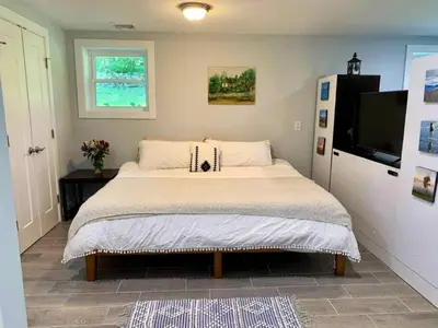 a bedroom with a large bed and a flat screen tv at The Suite at Pound Ridge in Pound Ridge