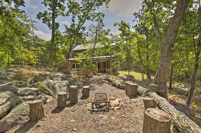 a dog laying in a yard with logs and a house at The Glabin Garrison Gem with Hot Tub and Fire Pit in Garrison