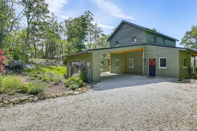a green house with a garage and a driveway at The Glabin Garrison Gem with Hot Tub and Fire Pit in Garrison