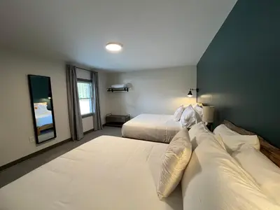 a large bedroom with two beds and a mirror at East Rock Inn in Great Barrington