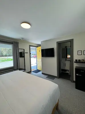 a large bedroom with a white bed and a television at East Rock Inn in Great Barrington