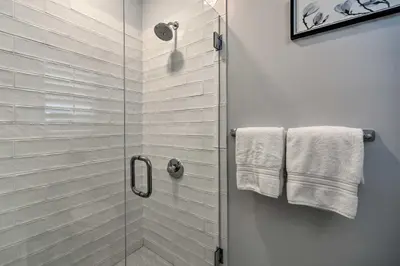 a bathroom with a glass shower with towels on the wall at Stunning House with Deck, Game Room and Home Gym! in Saratoga Springs