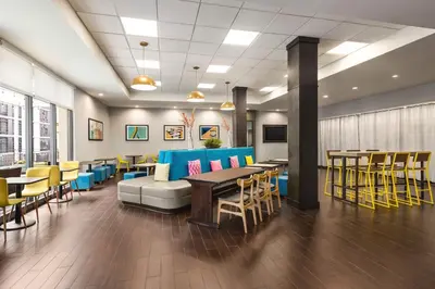 a restaurant with tables and chairs and a couch at Home2 Suites Long Island City/Manhattan View in Queens