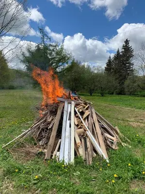a pile of wood on fire in a field at Harpersfield House /North West Catskills + sauna in Jefferson