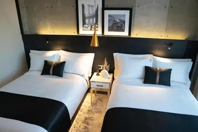 two beds in a room with white sheets and black pillows at 42 Hotel Williamsburg in Brooklyn