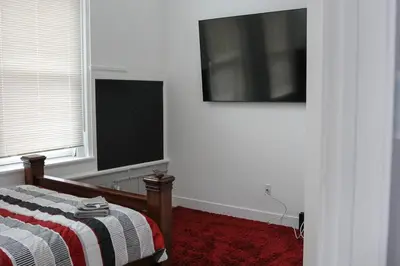 a bedroom with a bed and a television on the wall at A Luxurious 5 star Location 2 QUEEN Bed’s TROY in Troy