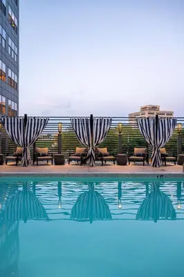 a pool with two umbrellas and chairs next to a building at Hyatus Luxury Residences City Crossing in New Haven