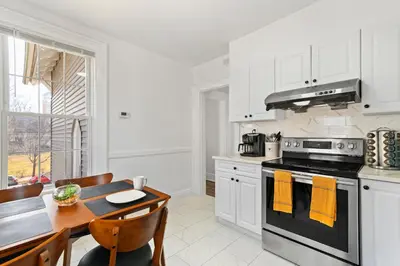 a white kitchen with a stove and a table at Orange Oasis in the Heart of East Rock with FREE parking near DT and Yale in New Haven