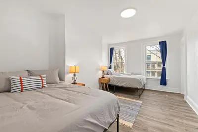 a white bedroom with two beds and a window at Orange Oasis in the Heart of East Rock with FREE parking near DT and Yale in New Haven